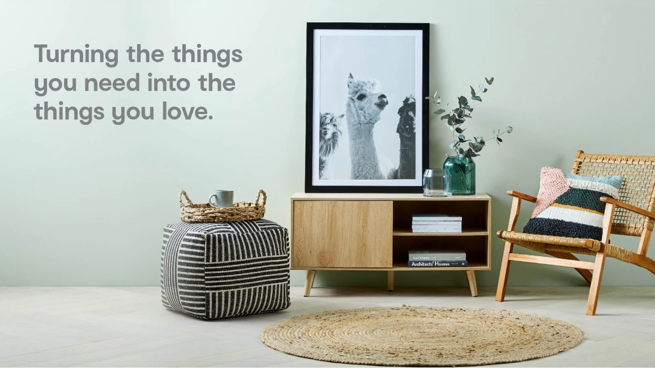 A photo showcasing home living room furniture and art with the text "Turning the things you need into the things you love."