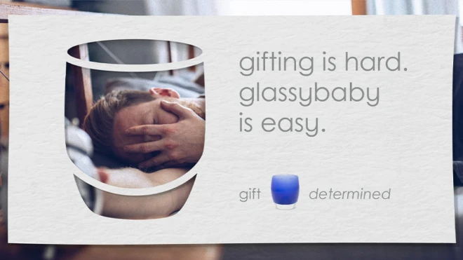 A person is holding their face in their hands. The text reads, "gifting is hard. Glassybaby is easy." Below the text, the words "gift" and "determined" are next to a blue votive.