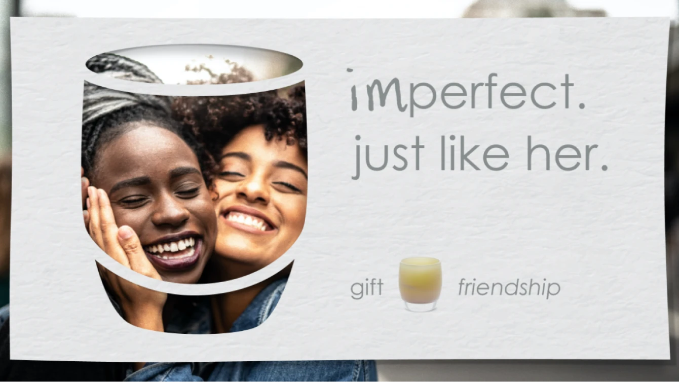 Two smiling women within a stylized glassybaby candle outline. Text reads 'imperfect. just like her.' with 'gift' and 'friendship' below.