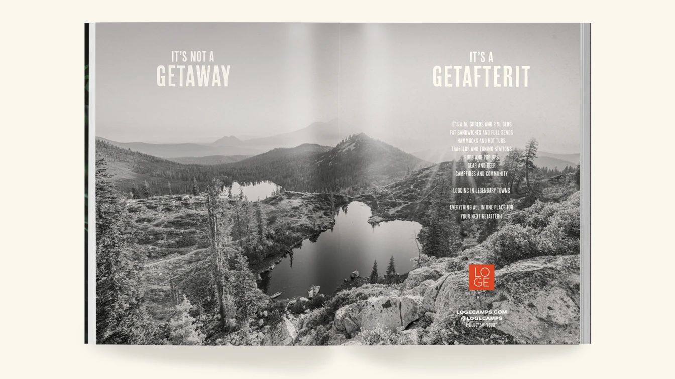 An open magazine spread with a scenic mountain landscape in black and white. On the left page, the text reads "IT'S NOT A GETAWAY" in bold, uppercase letters. On the right page, the text reads "IT'S A GETAFTERIT" in bold, uppercase letters. Below, a description highlights various activities and amenities such as morning shreds, comfortable beds, delicious sandwiches, hammocks, hot tubs, Traegers, tuning stations, gear, beer, campfires, and a sense of community. It emphasizes that everything needed for an adventure-filled stay is available in legendary towns, all in one place for the next "getafterit" experience. At the bottom right corner, there is a small red square with the white "LOGE" logo and the text "LOGECAMPS.COM @LOGECAMPS" below it.