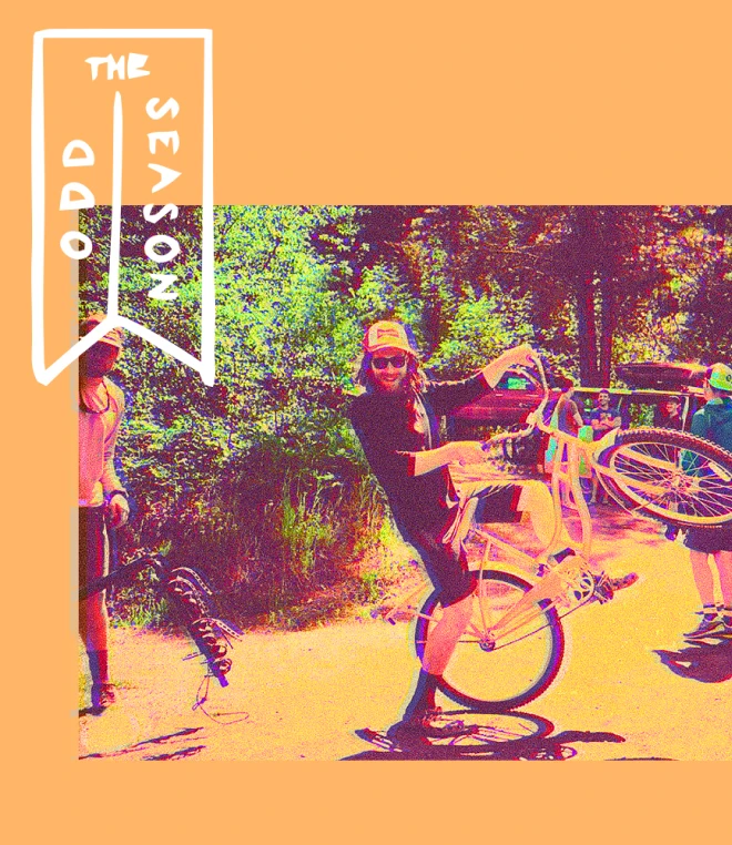 A man wearing sunglasses and a hat performs a wheelie on a bicycle near two others in front of a forested area. The image has a bright filter over it next to the text "The Odd Season".