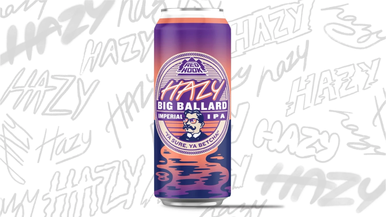 Red Hook Hazy Big Ballard Imperial IPA beer can with a purple and orange gradient background featuring the Hazy Big Ballard logo. The can displays a stylized image of a man with glasses and a mustache, accompanied by the slogan "Ya Sure, Ya Betcha." The background includes various iterations of the word "Hazy" in different fonts and styles.
