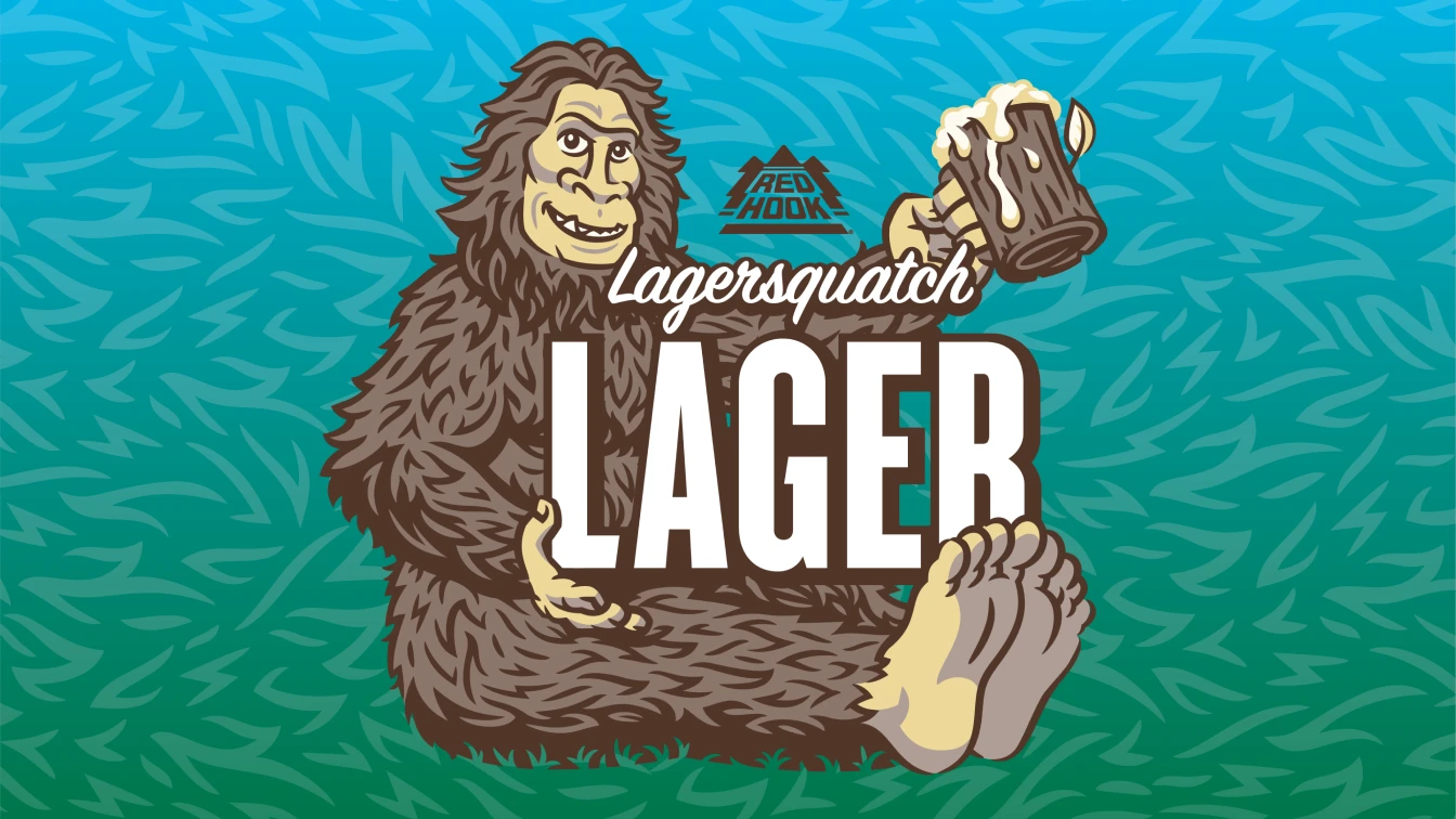 An illustration of a friendly sasquatch holding a frothy beer mug and reclining on a grassy background. The image text reads "Lagersquatch Lager" and with the Red Hook logo above. 