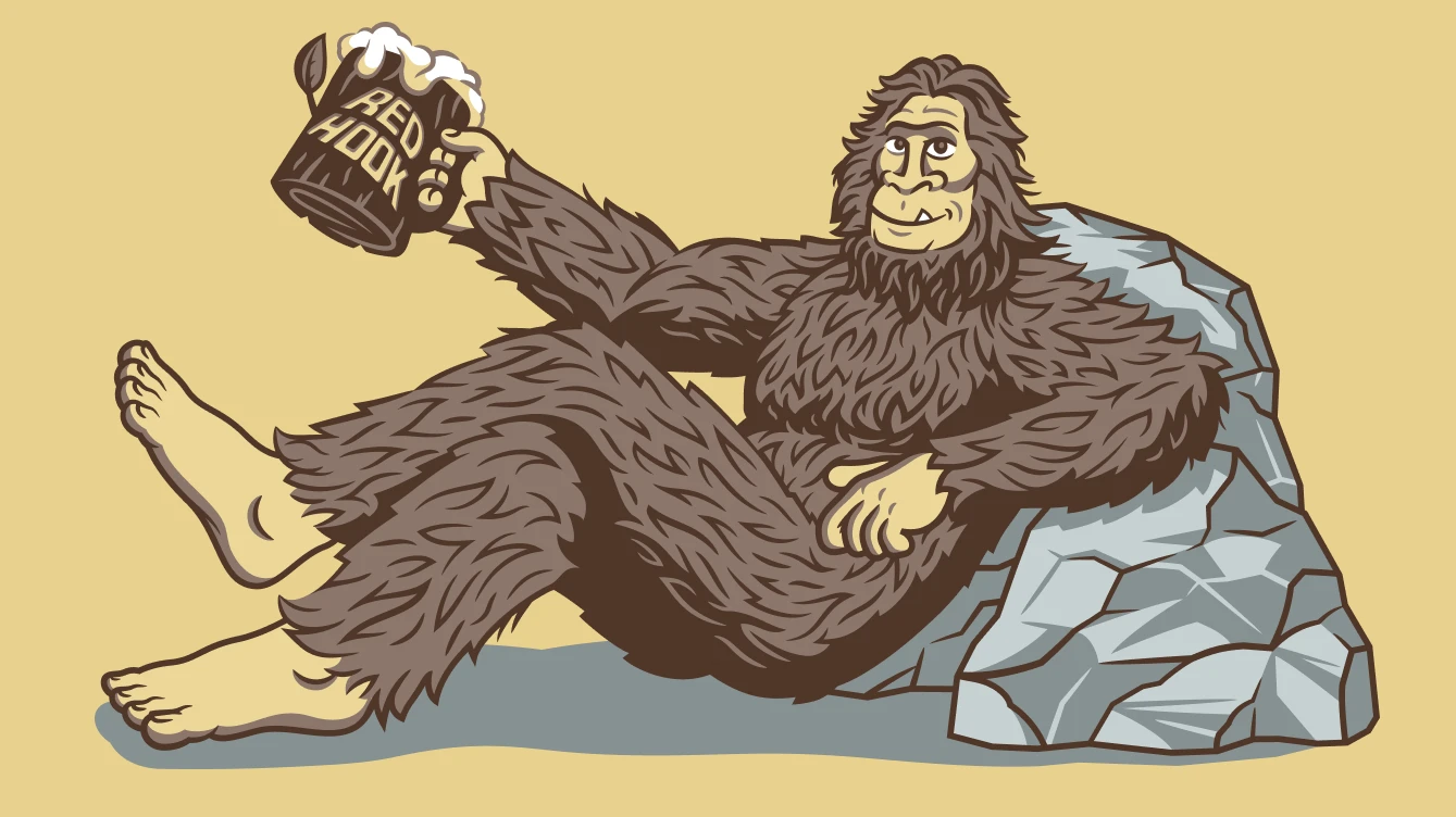 An illustration featuring a friendly sasquatch reclining against a large rock holding a frothy beer in a large wooden mug with the Red Hook logo.