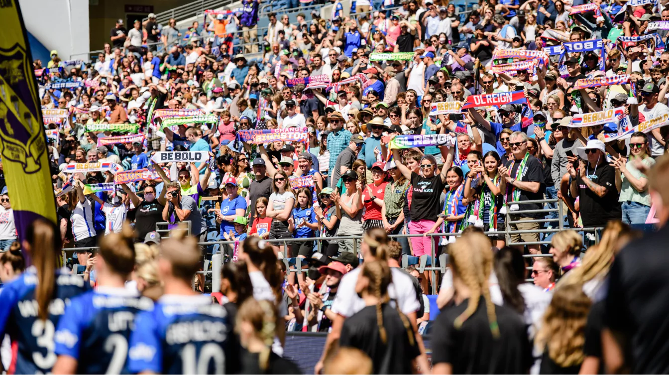 Enthusiastic soccer fans at a packed stadium, holding colorful scarves and cheering for their team, creating an energetic atmosphere.