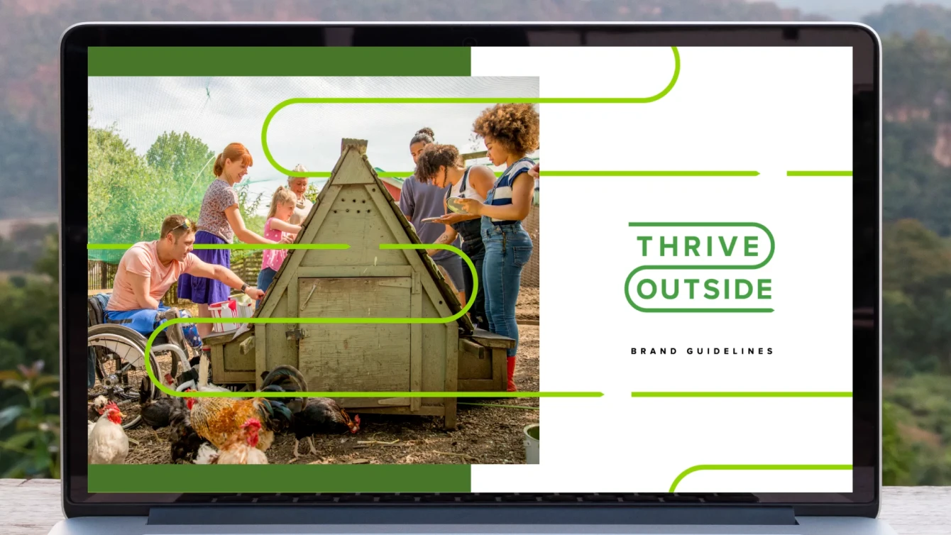 A laptop screen displays and image the text "Thrive Outside" and "brand guidelines". A group of individuals are shown working in a garden around a small wooden chicken coop and several chickens.