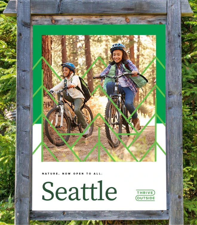 An outdoor advertisement for the "ThriveOutside" initiative in Seattle features two smiling children biking through a forest trail. They are both wearing helmets and backpacks.